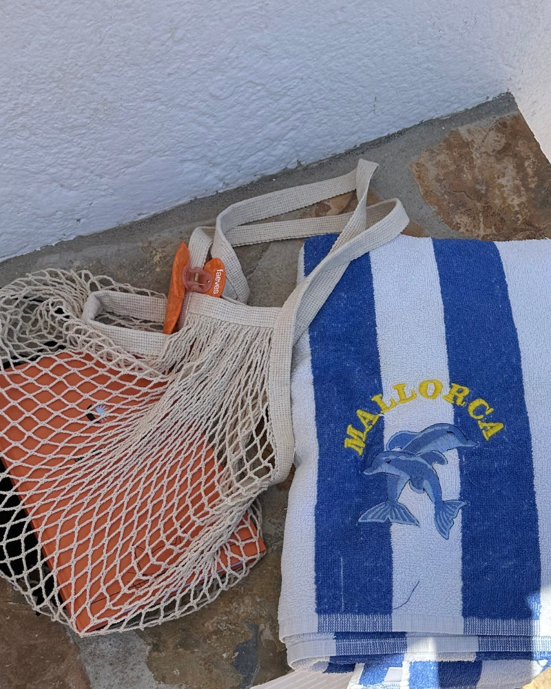 Close-up of a Mallorca towel and a net bag with Faeves products, perfect for a sunny beach day.