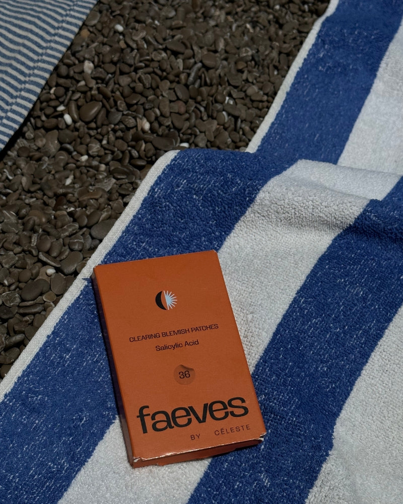 Faeves Clearing Blemish Patches placed on a blue and white striped beach towel, blending skincare essentials with a day at the beach.