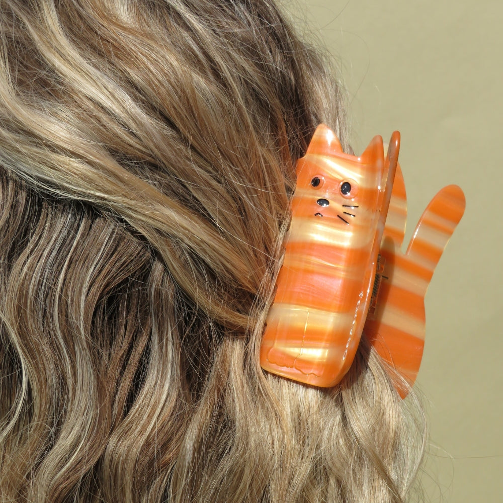 
                  
                    Close-up of a Cat Claw Clip from Faeves, featuring a cute cat-shaped design with detailed ears and facial features. The clip is shown securing hair, highlighting its strong hold and the intricate detailing of the cat shape.
                  
                