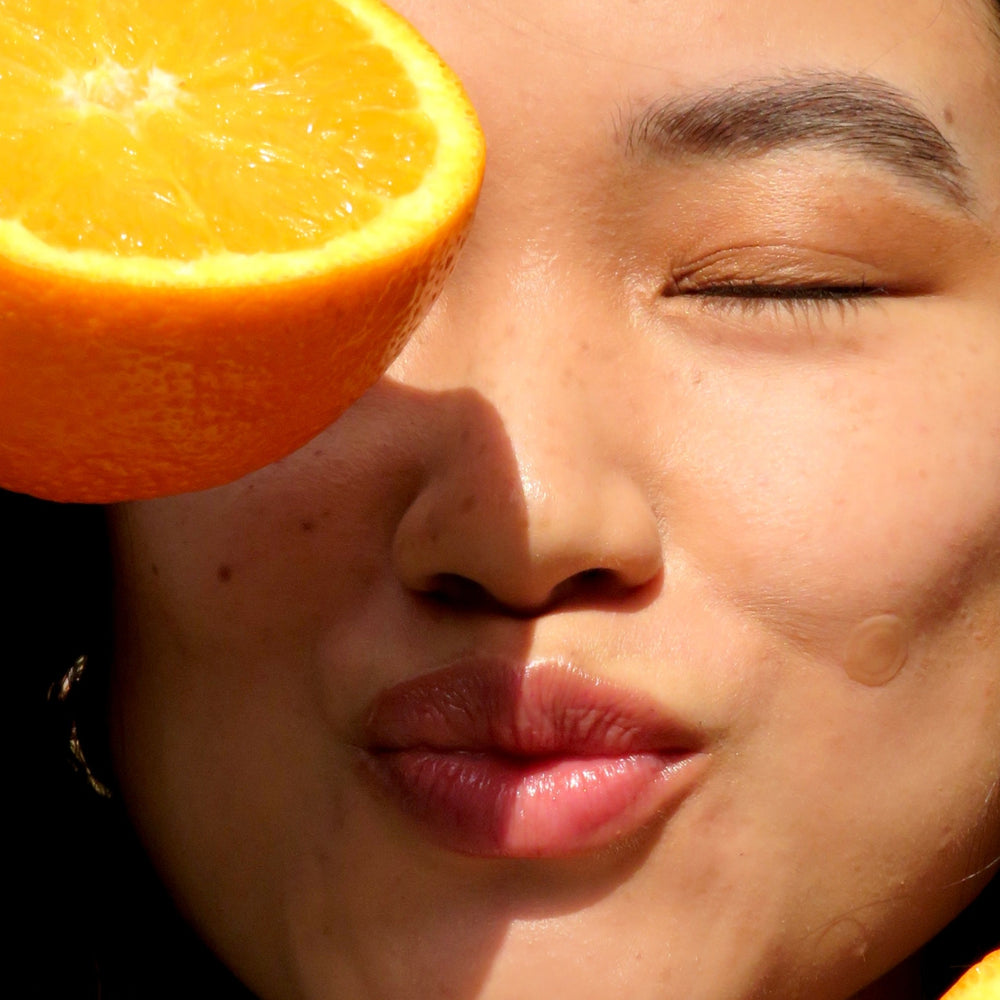 Homepage banner featuring a woman holding an orange slice over her eye with a Faeves skincare patch on her cheek, highlighting the natural and vibrant approach of Faeves.