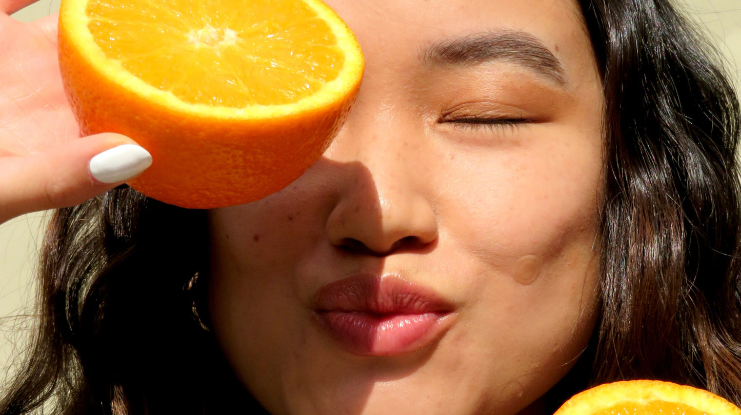 Homepage banner featuring a woman holding an orange slice over her eye with a Faeves skincare patch on her cheek, highlighting the natural and vibrant approach of Faeves.