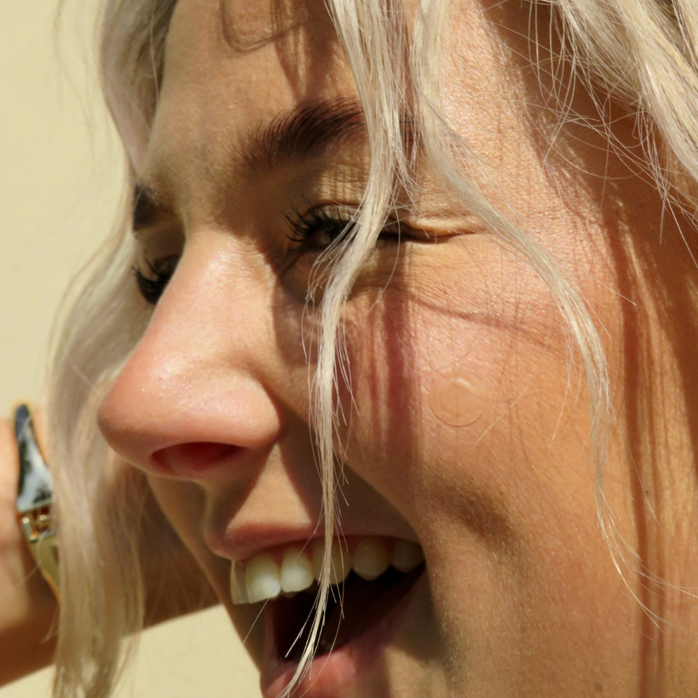 
                  
                    Close-up of a smiling woman with a Faeves blemish patch on her cheek, illustrating the application process in the 'How to Use' guide.
                  
                