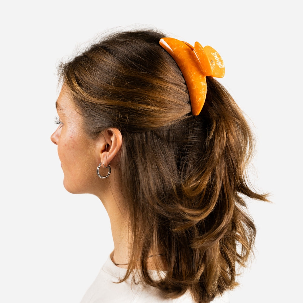 Orange claw clip designed for thick hair, perfect for holding various hairstyles securely in place.